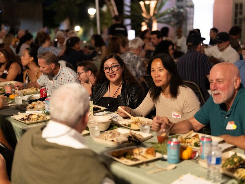 Guests in conversation over dinner at a long shared table